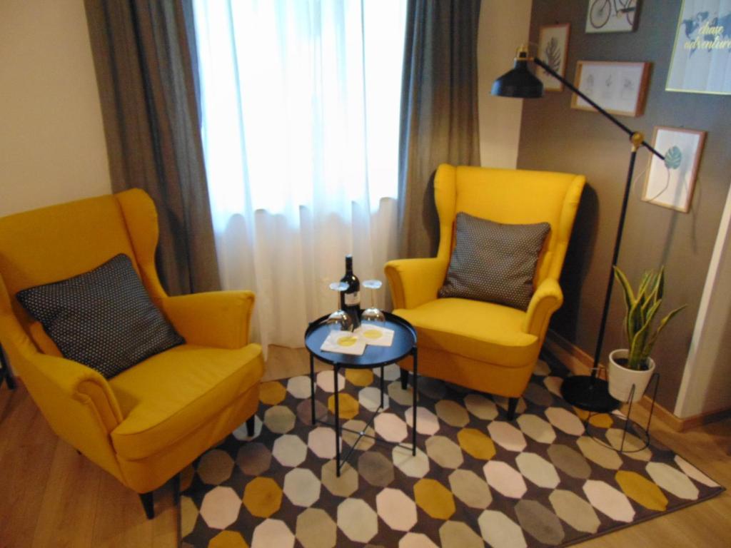 2 gelbe Stühle und ein Tisch im Wohnzimmer in der Unterkunft Apartments Glam in Poreč