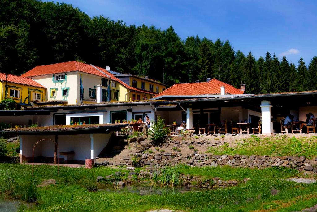 a group of buildings with tables and chairs next to a river at Hotel Hüttenmühle Hillscheid in Hillscheid