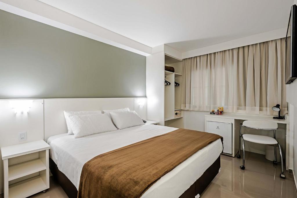 a hotel room with a large bed and a desk at Slim Curitiba João Bettega by Slaviero Hotéis in Curitiba