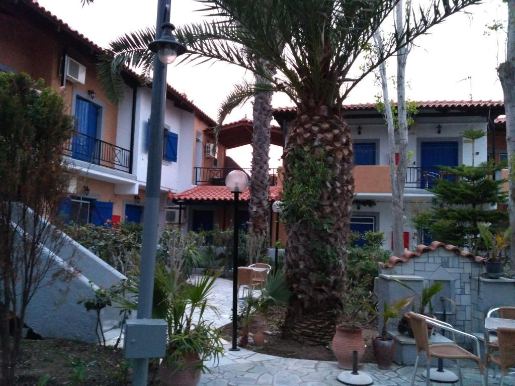 a courtyard with palm trees and a building at 9 Musses Hotel Apartments in Skala Mistegnon