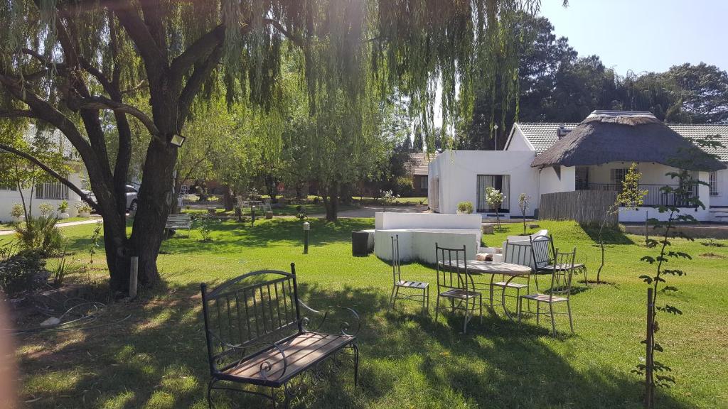 a yard with a table and chairs under a tree at SimbaSun Cottages in Midrand