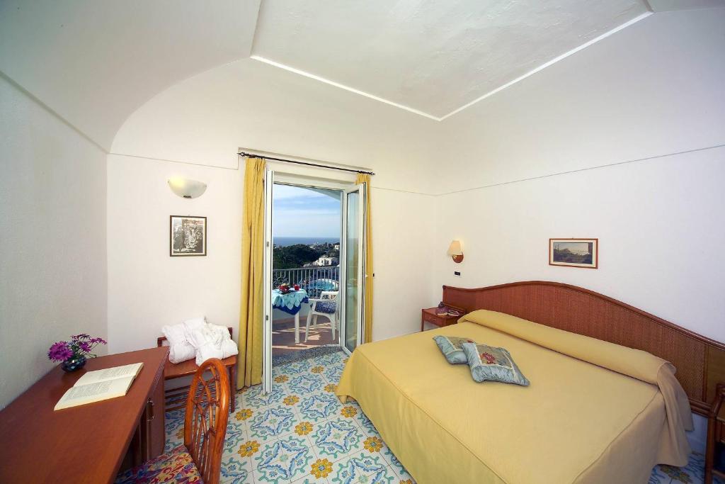 1 dormitorio con cama, escritorio y ventana en Hotel Terme Villa Teresa en Isquia