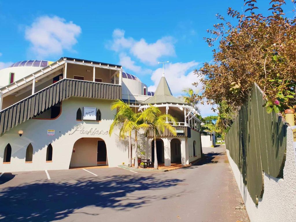 a white building with a palm tree next to a street at Parklane Motor Lodge in Auckland