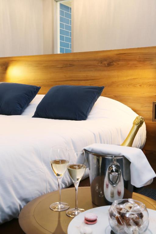 - un lit avec 2 verres de vin sur une table dans l'établissement Hôtel Restaurant Les Grains d'Argent Dizy - Epernay, à Épernay