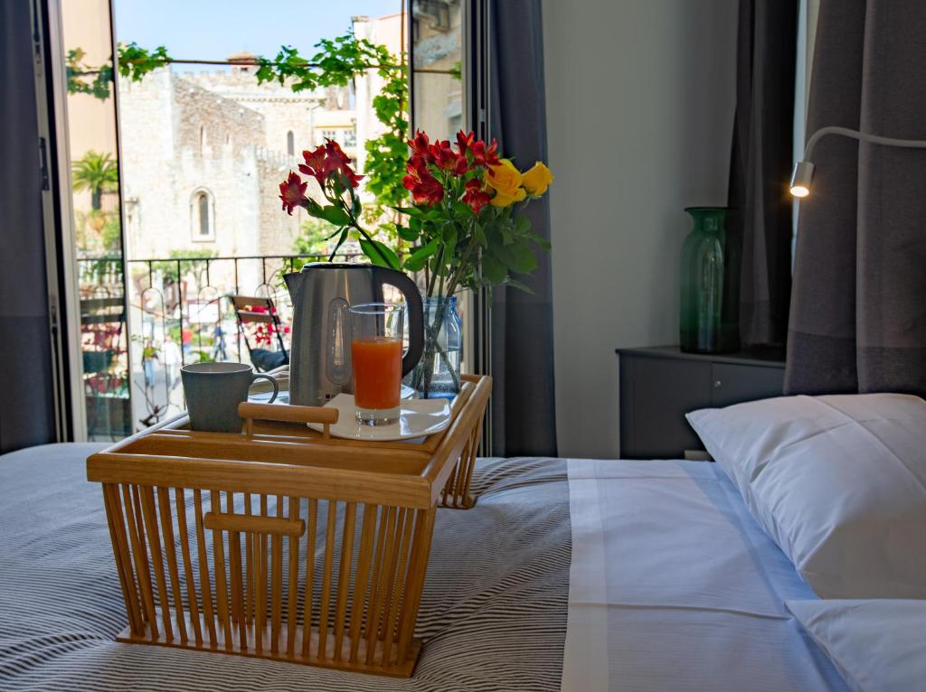 タオルミーナにあるTaoMau - Duomo Squareのベッドの上にテーブルとオレンジジュース1杯