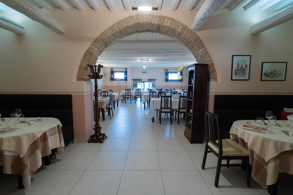 a dining room with tables and chairs and an archway at Hotel Ristorante Cantina Langelina in Corinaldo