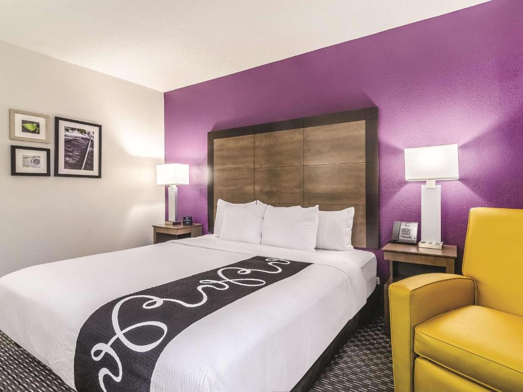 a hotel room with a large bed and a yellow chair at La Quinta by Wyndham Myrtle Beach - N. Kings Hwy in Myrtle Beach