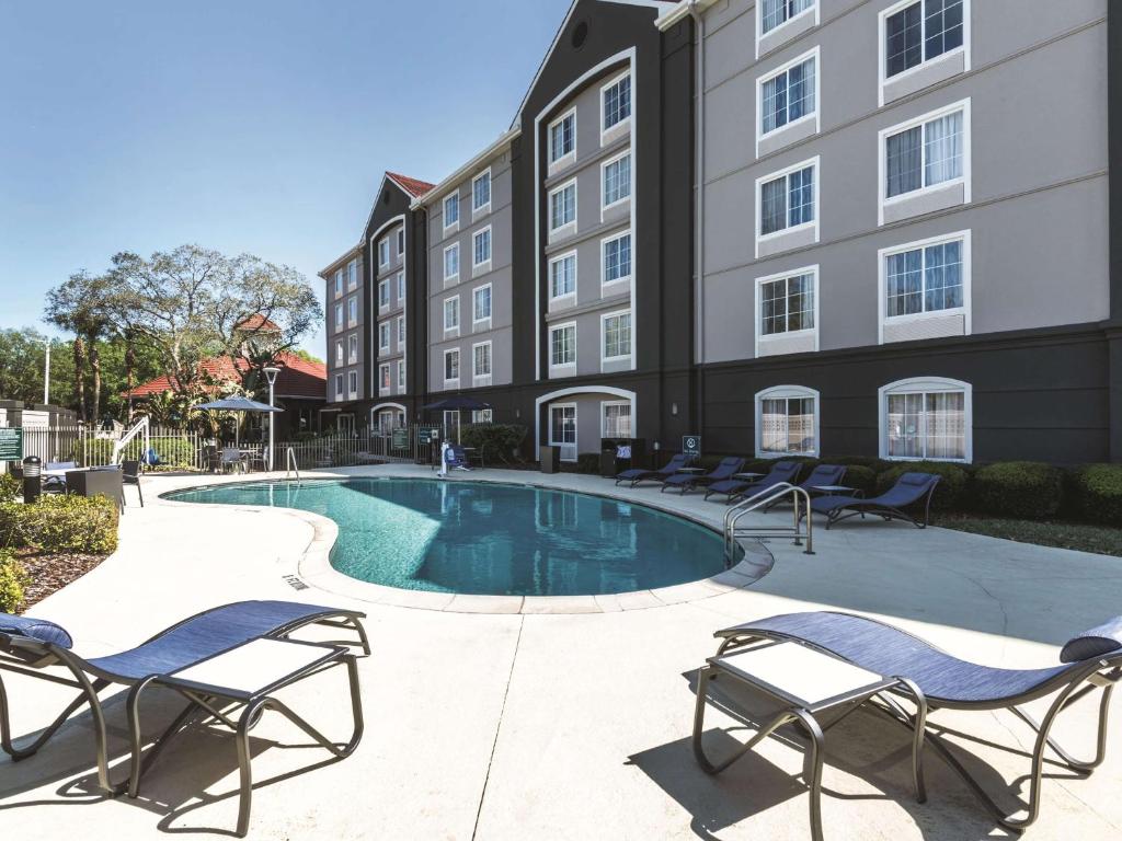uma piscina num hotel com cadeiras e um edifício em La Quinta by Wyndham Orlando Lake Mary em Lake Mary