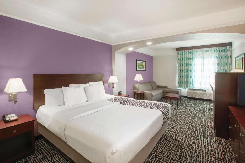 Cama grande en habitación de hotel con paredes púrpuras en La Quinta by Wyndham Mansfield TX, en Mansfield