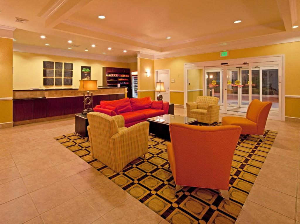 uma sala de estar com um sofá vermelho e cadeiras em La Quinta by Wyndham Mobile - Tillman's Corner em Mobile