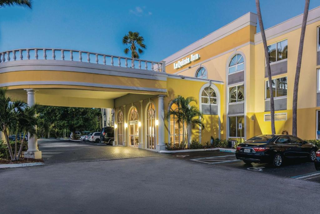 a yellow building with a car parked in a parking lot at La Quinta Inn by Wyndham Jupiter in Jupiter