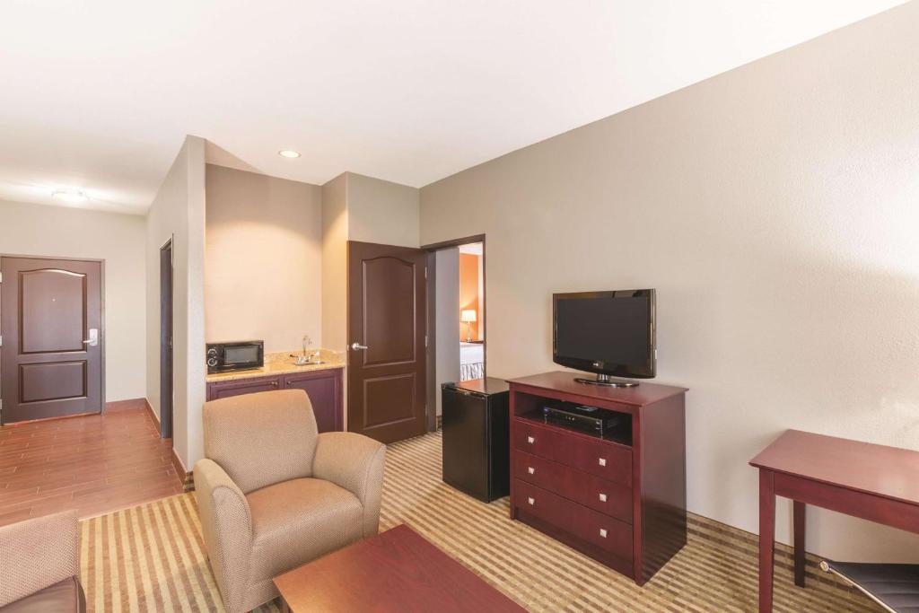 a living room with a tv and a couch and a chair at La Quinta by Wyndham Houston IAH Bush Intl Airport E in Humble