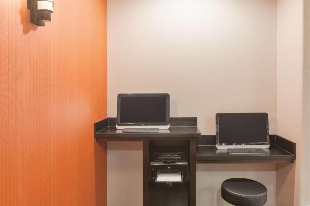 a desk with two computers on top of it at La Quinta by Wyndham Houston IAH Bush Intl Airport E in Humble