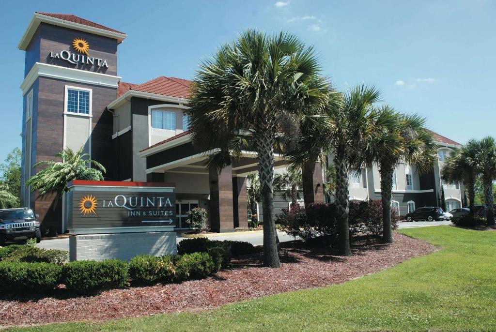 un hôtel avec des palmiers devant un bâtiment dans l'établissement La Quinta by Wyndham Baton Rouge Denham Springs, à Bâton-Rouge