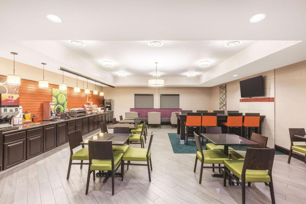 a restaurant with tables and chairs and a cafeteria at La Quinta by Wyndham Houston IAH Bush Intl Airport E in Humble