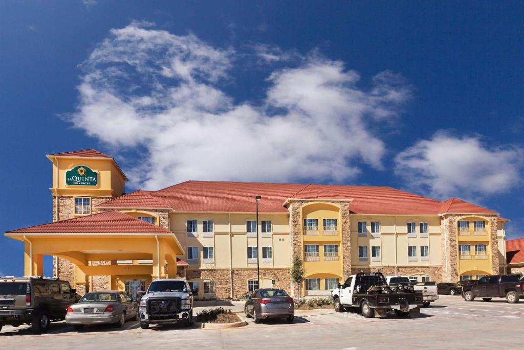 a hotel with cars parked in a parking lot at La Quinta by Wyndham Floresville in Floresville