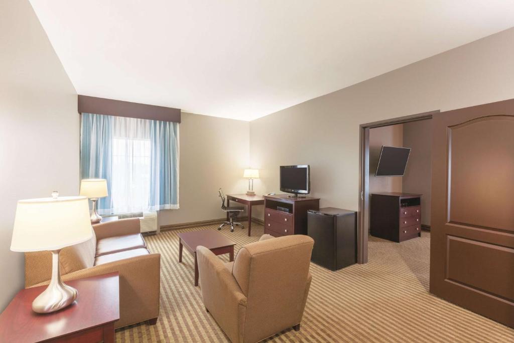 a hotel room with a couch and a chair and a television at La Quinta by Wyndham Houston IAH Bush Intl Airport E in Humble