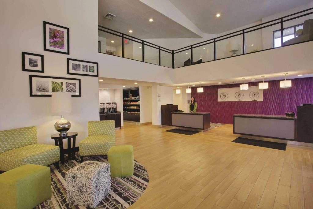 a lobby with a waiting area with chairs and tables at La Quinta Inn & Suites by Wyndham Detroit Metro Airport in Romulus