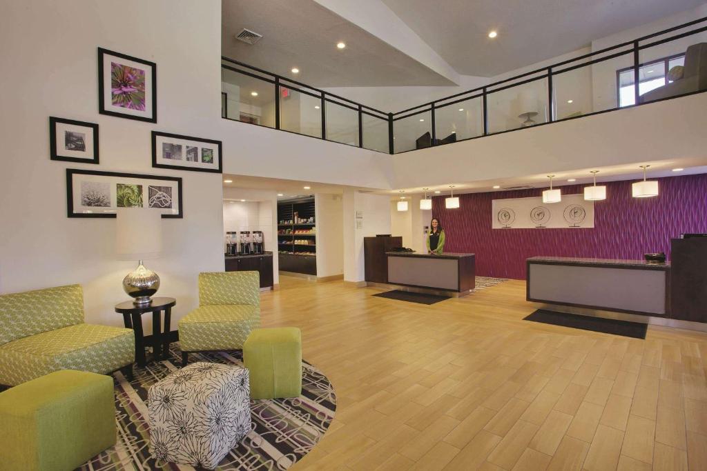 un vestíbulo con una zona de espera con sillas y mesas en La Quinta Inn & Suites by Wyndham Detroit Metro Airport, en Romulus