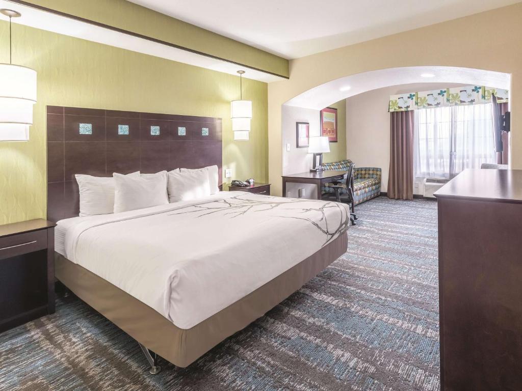 a hotel room with a large bed and a desk at La Quinta by Wyndham Dallas Grand Prairie South in Grand Prairie