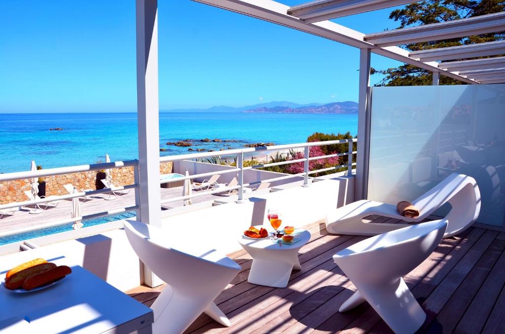 a balcony with white chairs and a view of the ocean at Résidence Dary in LʼÎle-Rousse