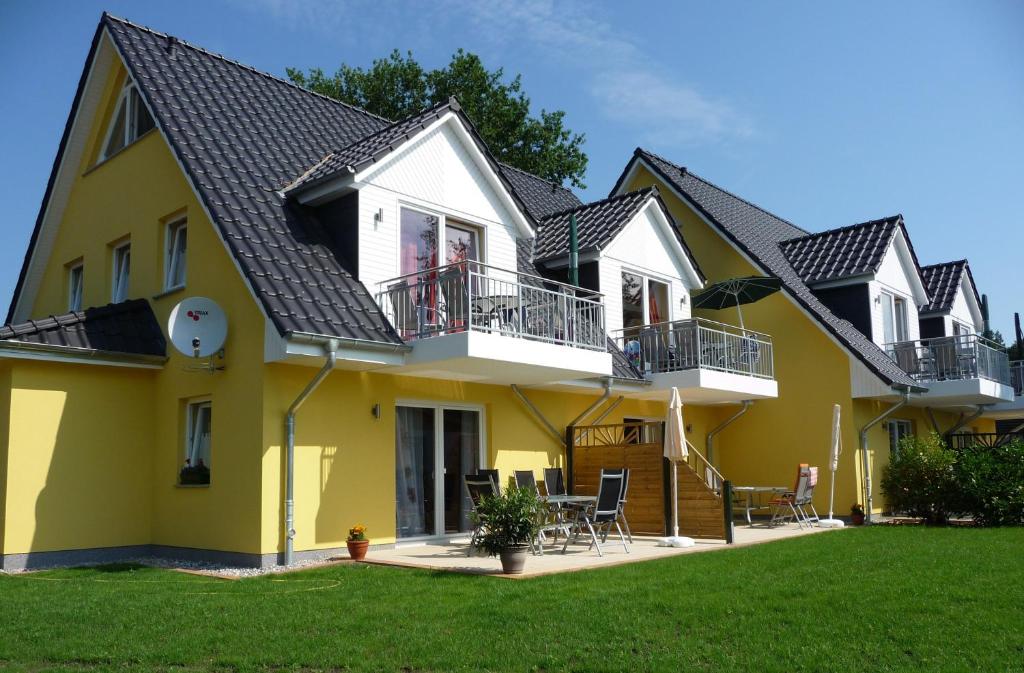 una casa amarilla con techo negro en Family Apartments Tom, en Ostseebad Karlshagen