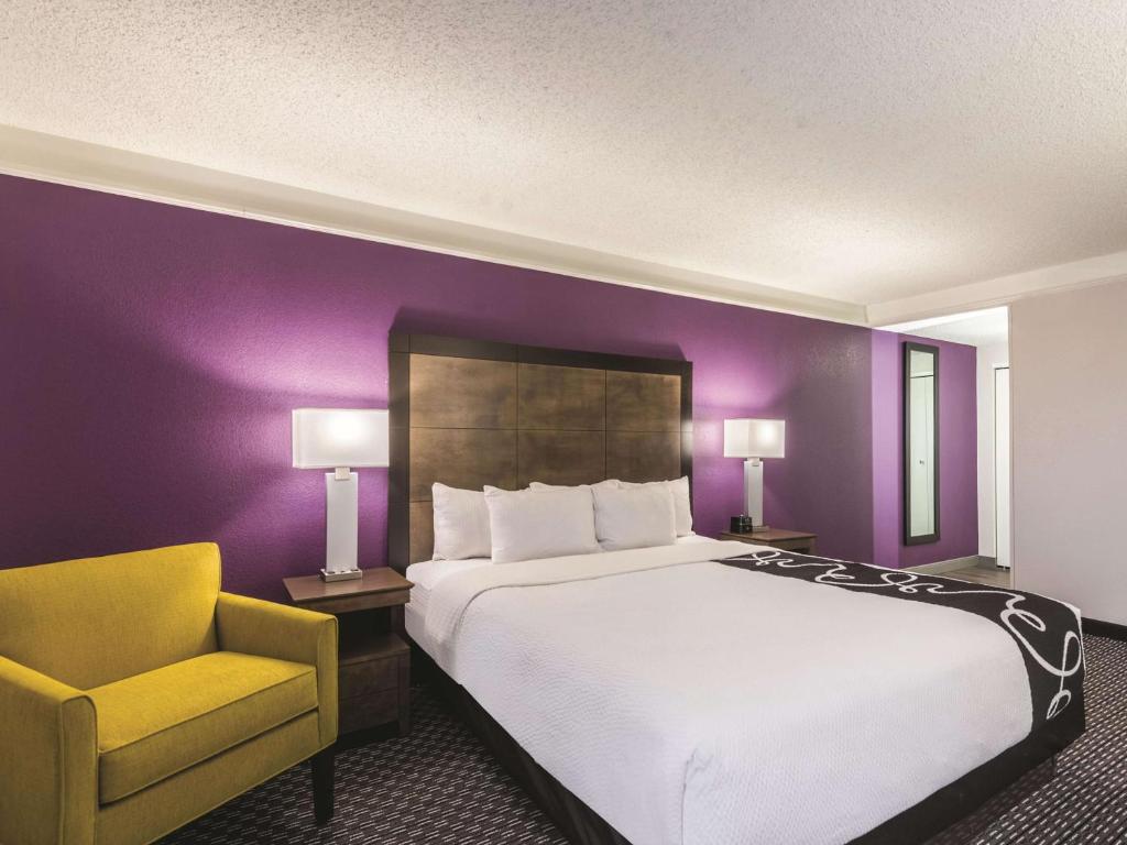 La Quinta by Wyndham Cincinnati Sharonville في شارونفيل: غرفة نوم بسرير كبير وكرسي اصفر