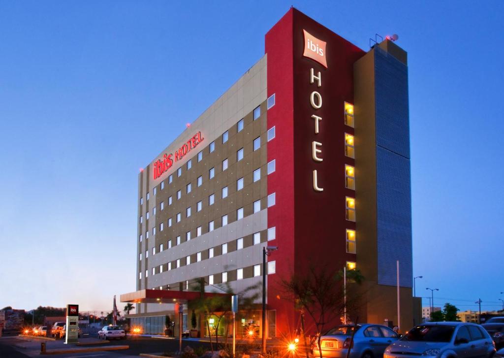 a hotel building with cars parked in a parking lot at Ibis Hermosillo in Hermosillo