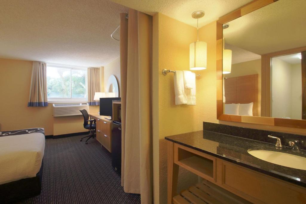 a hotel room with a bathroom with a sink and a mirror at La Quinta I-95 Deerfield Beach - Next to The Home Depot & Behind The Wawa in Deerfield Beach