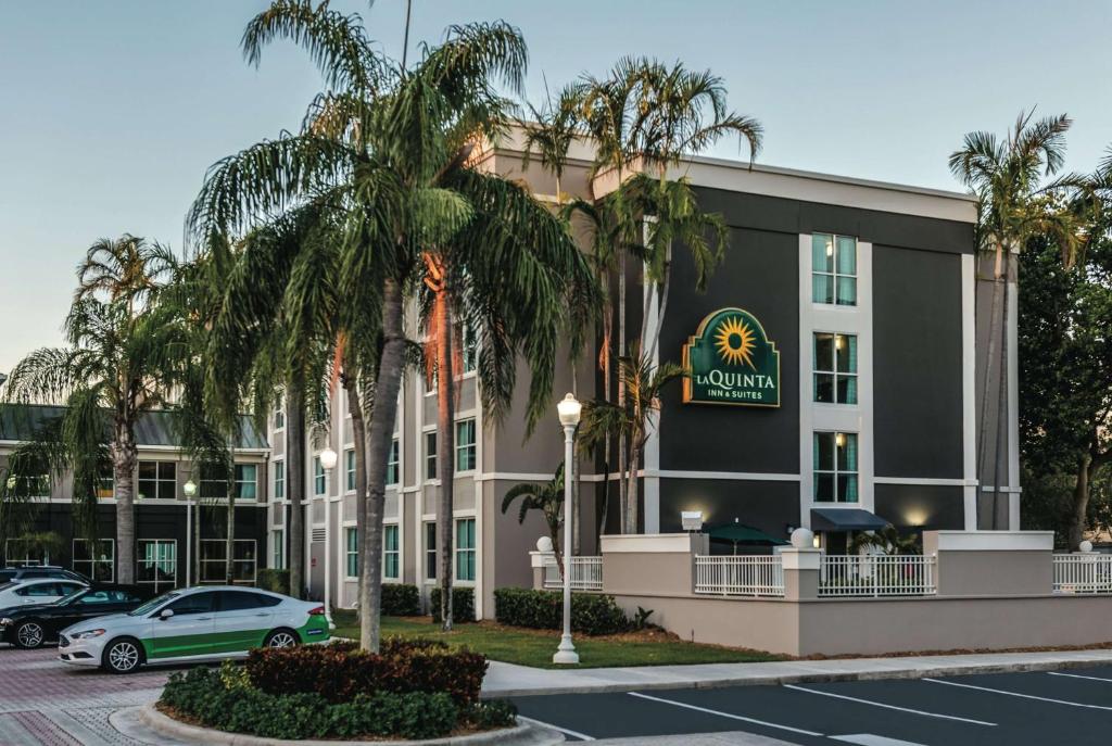 a hotel with palm trees in front of a parking lot at La Quinta by Wyndham Plantation at SW 6th St in Plantation