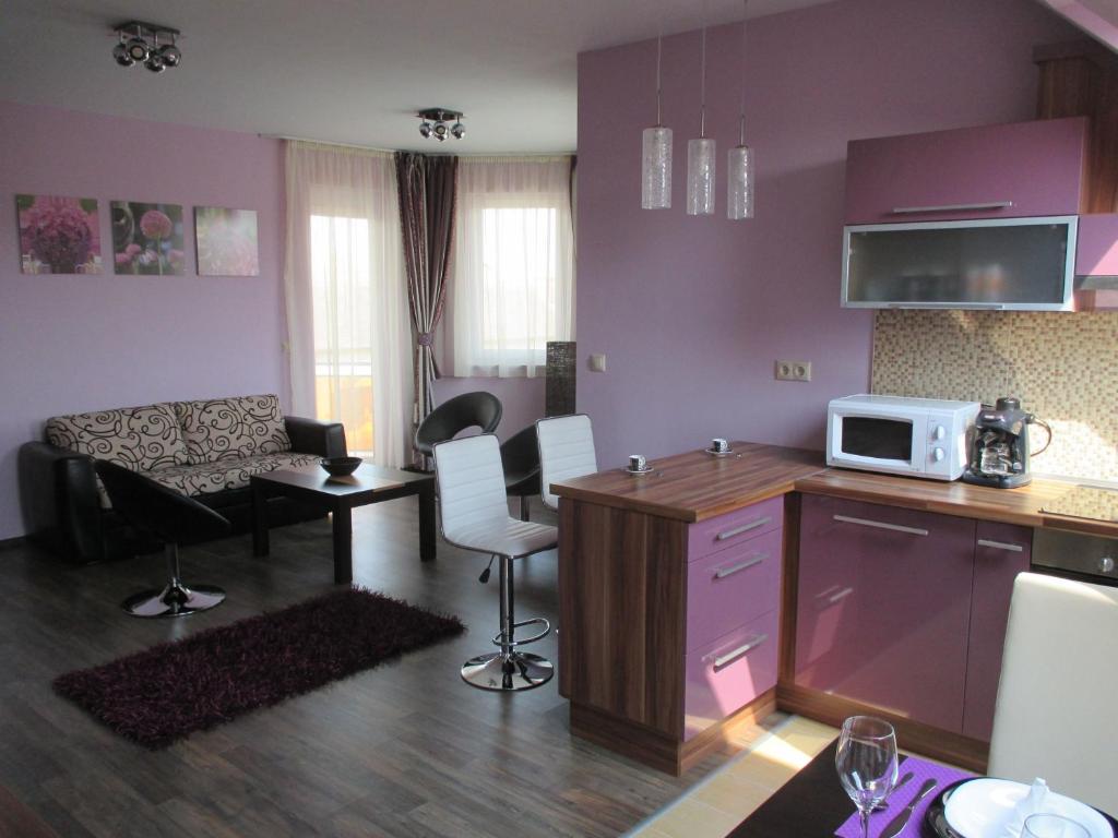 uma cozinha e sala de estar com paredes roxas e um micro-ondas em Alpha Apartman Sárvár em Sárvár