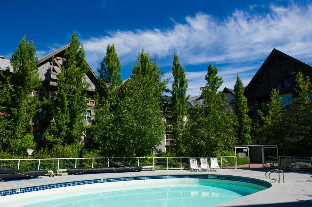 uma piscina em frente a um edifício com árvores em The Aspens by Whiski Jack em Whistler