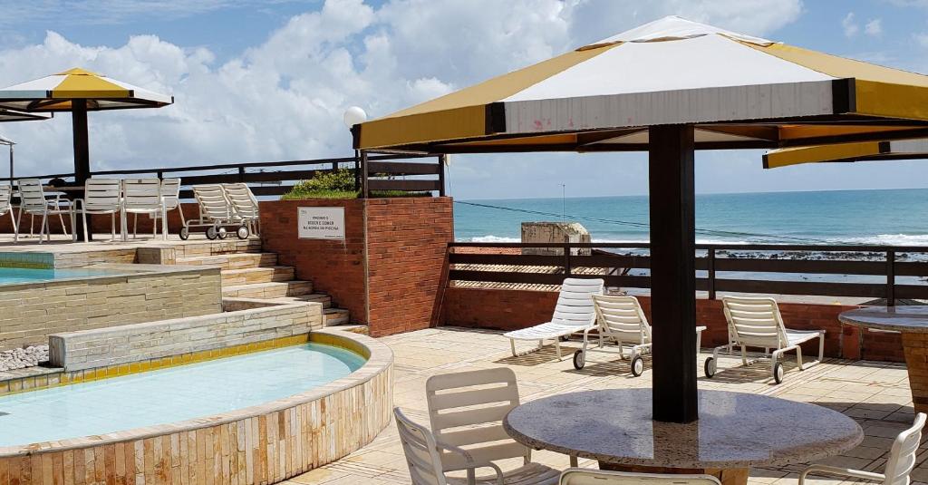 une terrasse avec une table, des chaises et un parasol dans l'établissement Pipa's Ocean - Flat Vista Mar, à Pipa