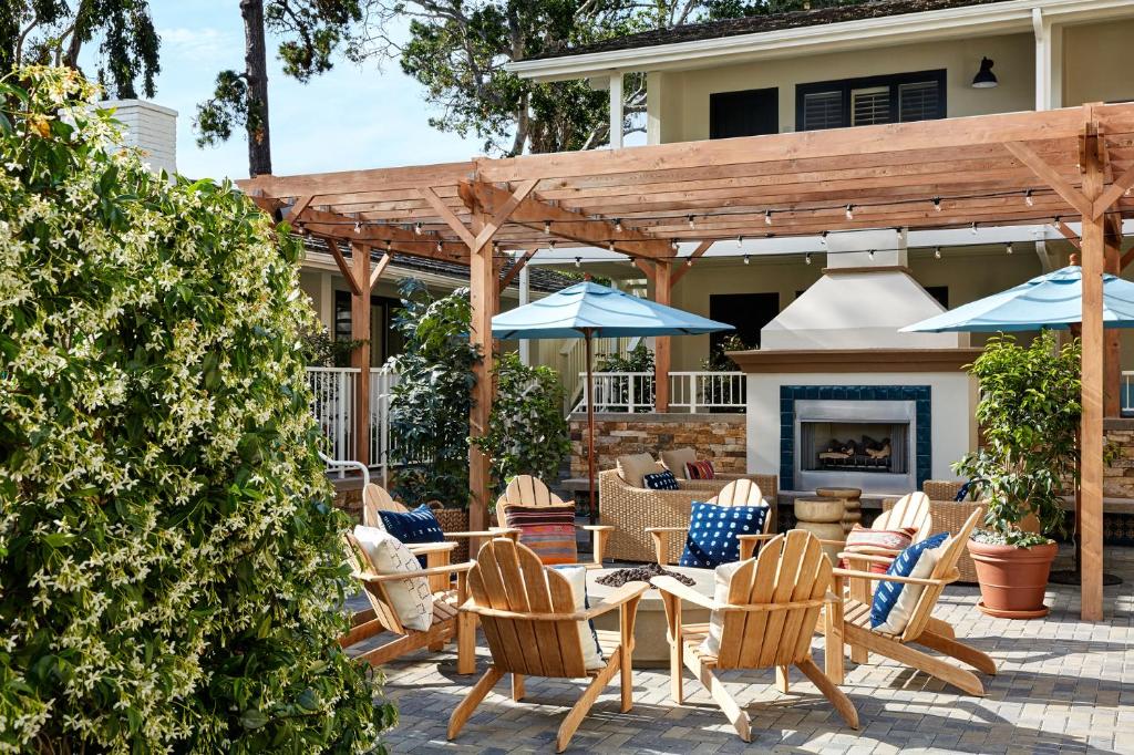 eine Terrasse mit Stühlen, Tischen und einem Kamin in der Unterkunft Hotel Carmel in Carmel