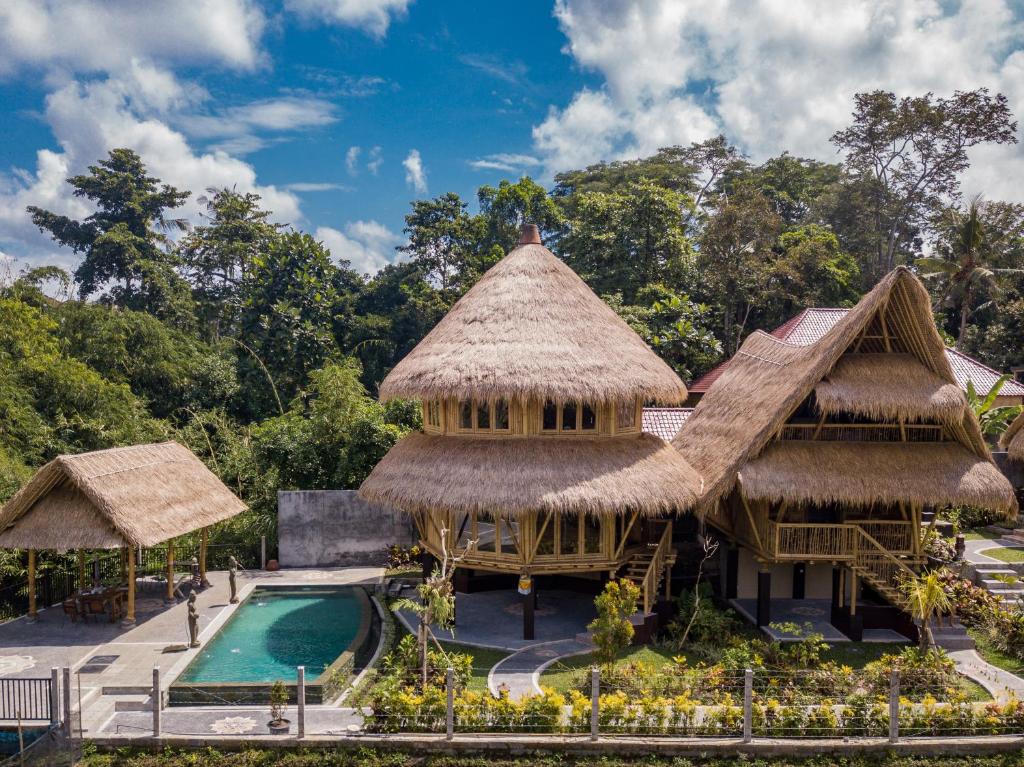 un complexe avec une piscine et un bâtiment au toit de chaume dans l'établissement Le Sabot Ubud, à Ubud