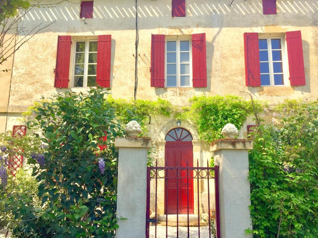 una vecchia casa con finestre con persiane rosse e un cancello di LA CARRETERIE - Les Gîtes a Pineuilh