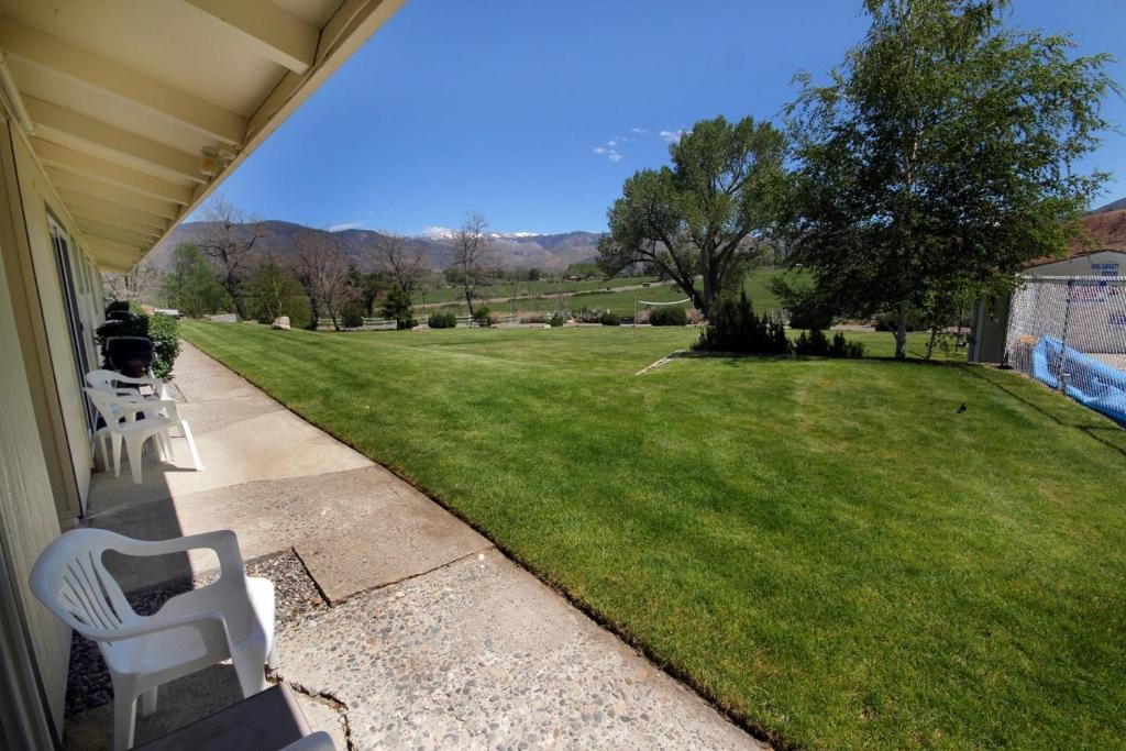 a porch with two white chairs and a green field at Meadowcliff Lodge Coleville in Coleville