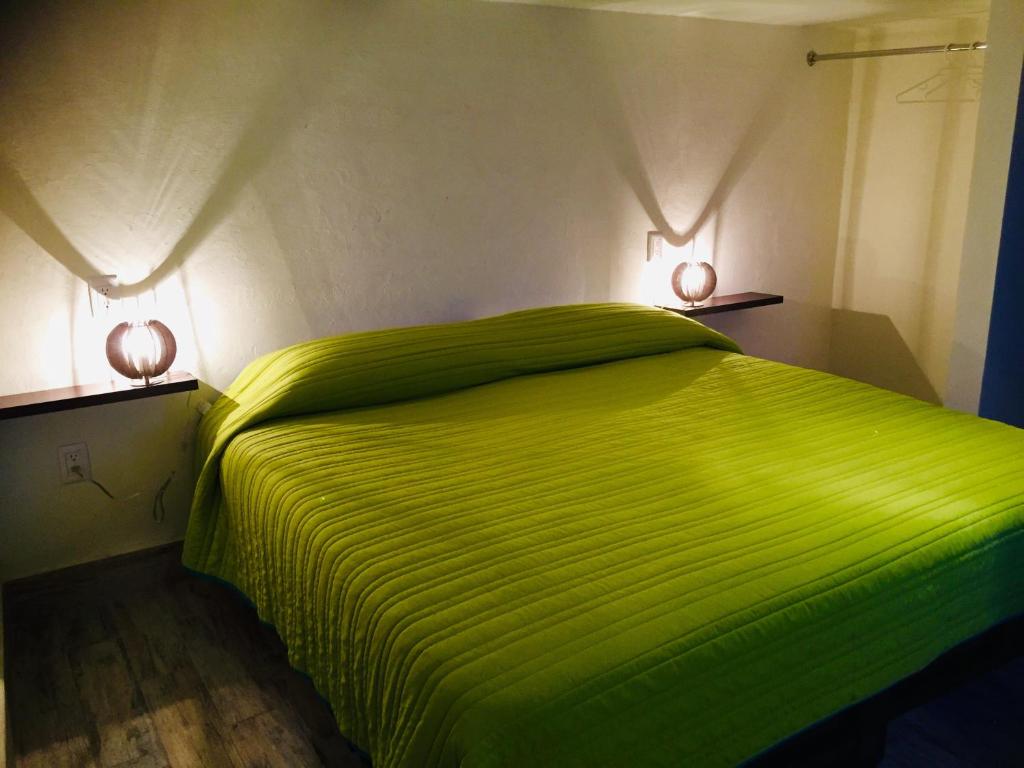 um quarto com uma cama verde com duas luzes em Mi Depa Canela en pleno Centro de la Ciudad em Ciudad Valles