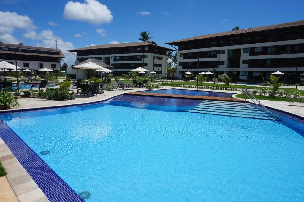 une grande piscine en face de certains bâtiments dans l'établissement Deluxe Cupe Beach Living, à Porto de Galinhas