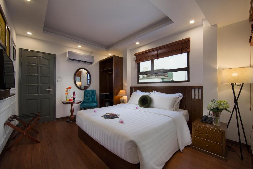 Un dormitorio con una gran cama blanca y una ventana en Hanoi Amber Hotel, en Hanói