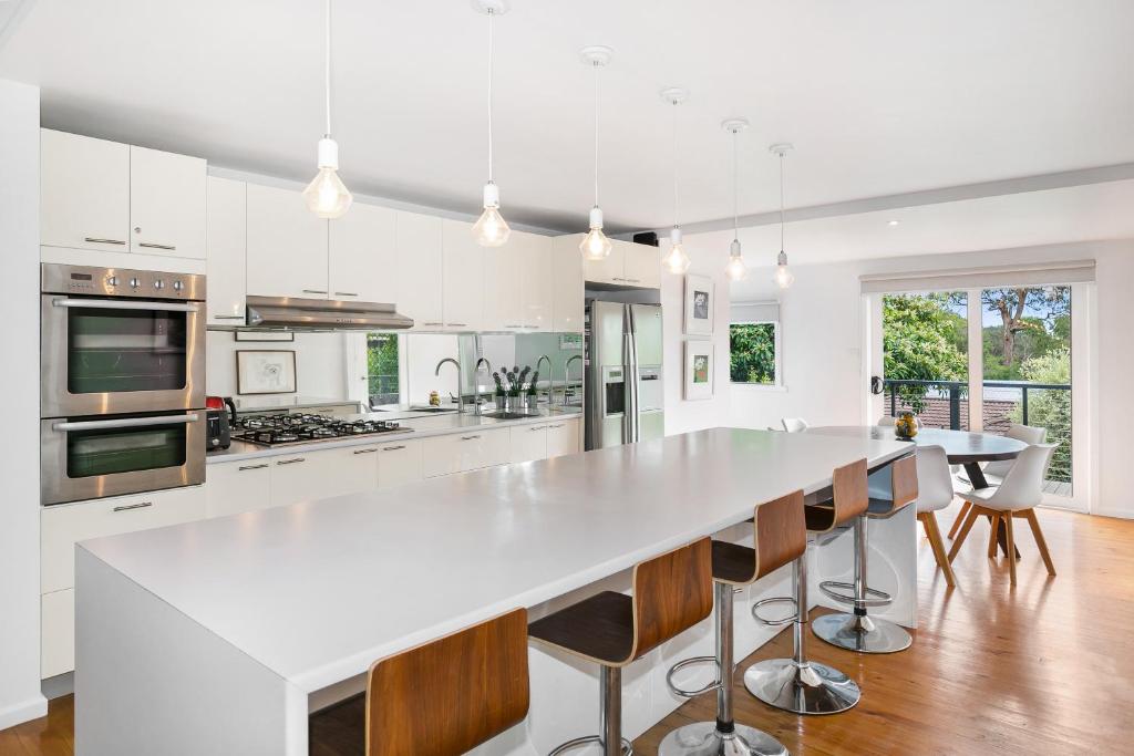 a white kitchen with a large white island with bar chairs at Foreva Rye in Rye