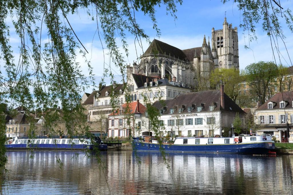 une ville avec des bateaux dans l'eau en face d'un château dans l'établissement Hôtel Le Maxime - Best Western Signature Collection, à Auxerre
