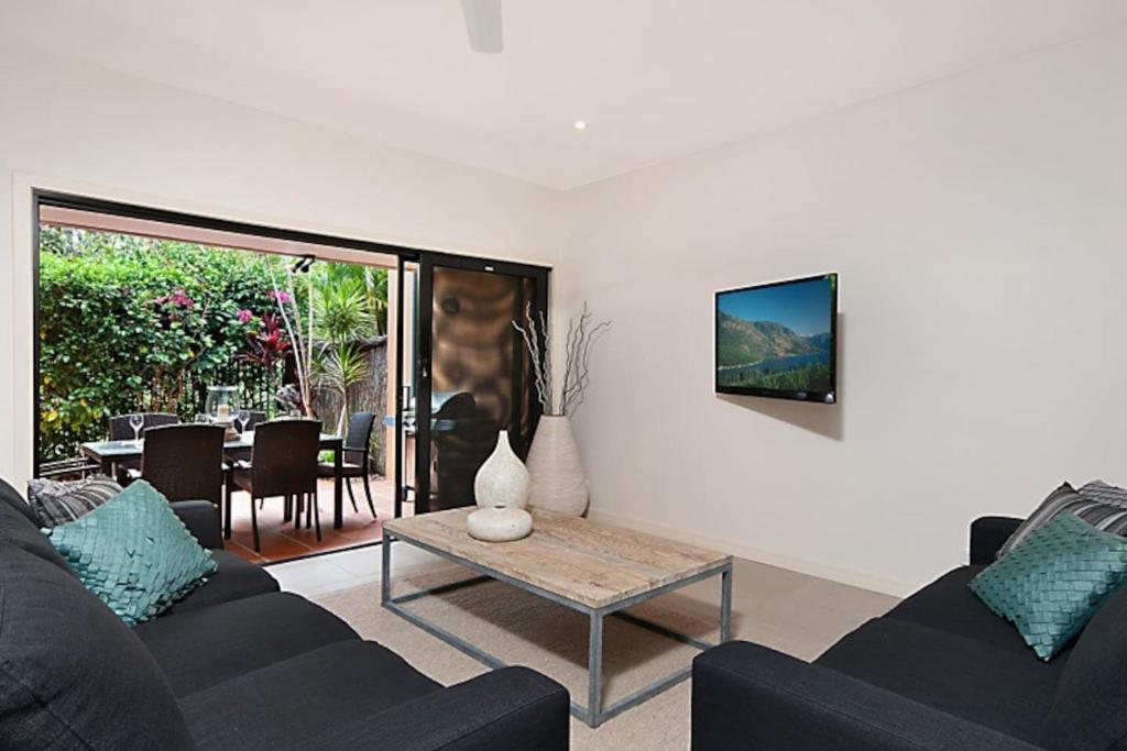 a living room with a couch and a table at Cavvanbah Beach Villa in Byron Bay