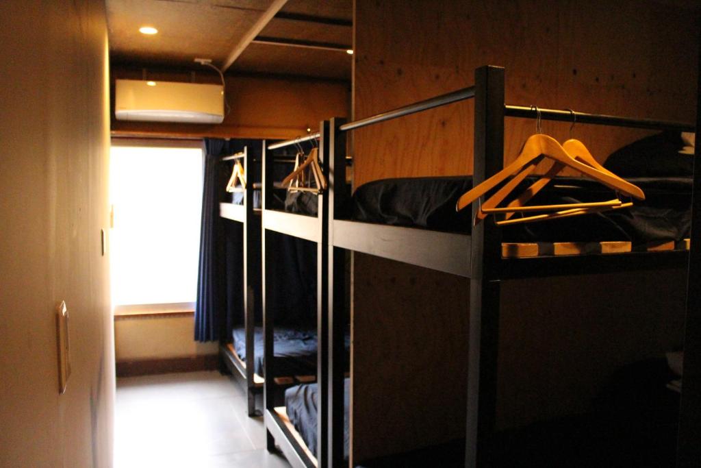 a room with two bunk beds in a room at Kamp Houkan-cho Backpacker's Inn & Lounge in Okayama