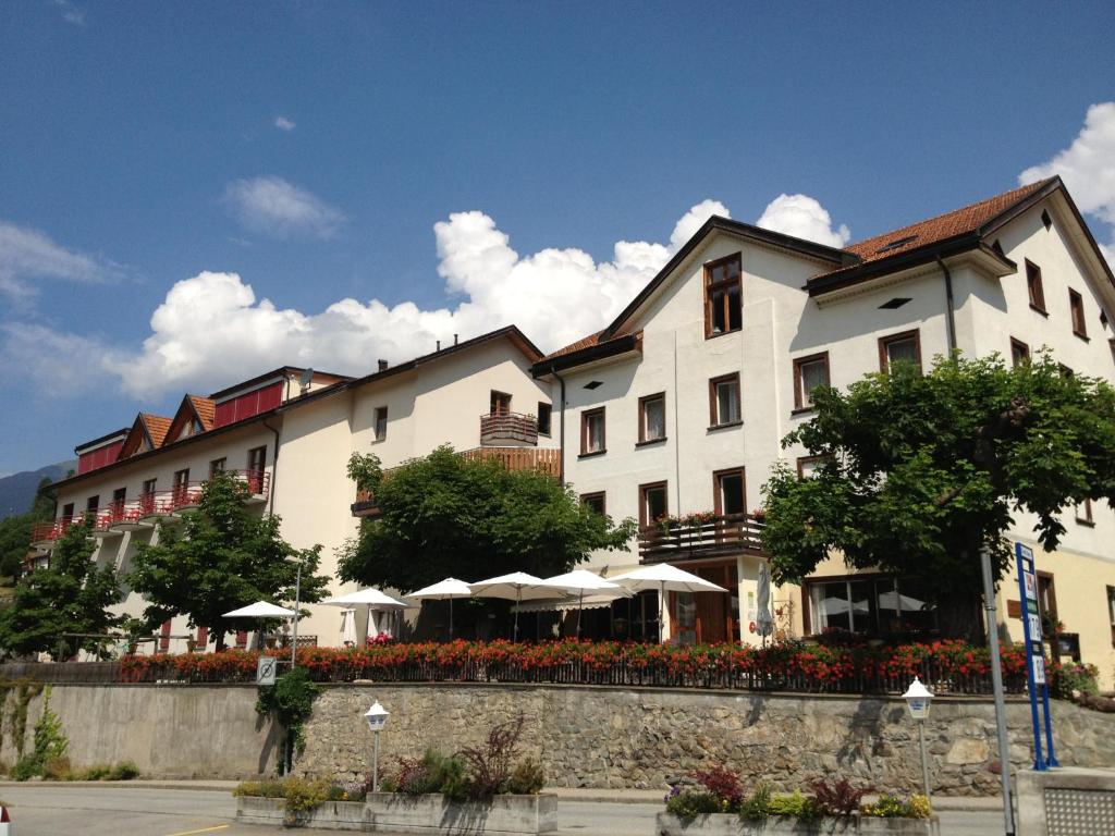 ein großes weißes Gebäude mit Sonnenschirmen davor in der Unterkunft Hotel Schöntal in Filisur