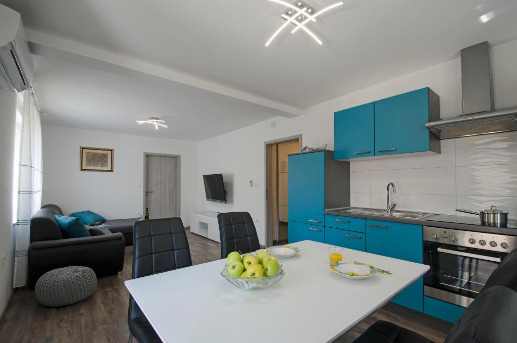 a kitchen with blue cabinets and a table with a bowl of fruit at Apartment Pula R&D in Pula