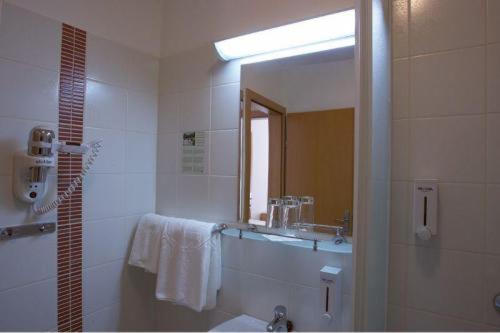 a bathroom with a shower and a sink and a mirror at Hotel Panonija in Sisak