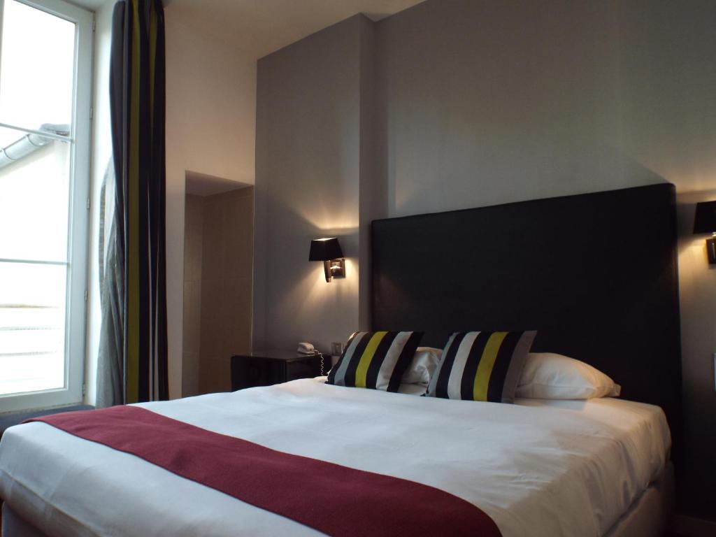 sypialnia z dużym łóżkiem i dużym oknem w obiekcie Hôtel Saint Martin w Orleanie