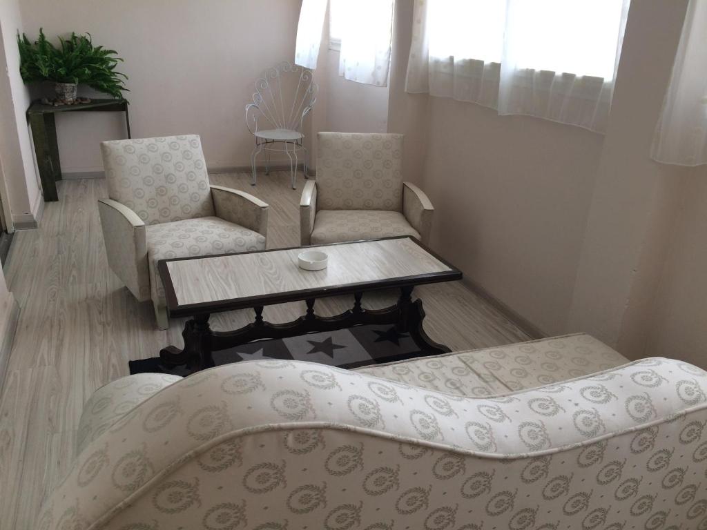 uma sala de estar com um sofá, uma mesa e cadeiras em Apartman Melody em Sombor