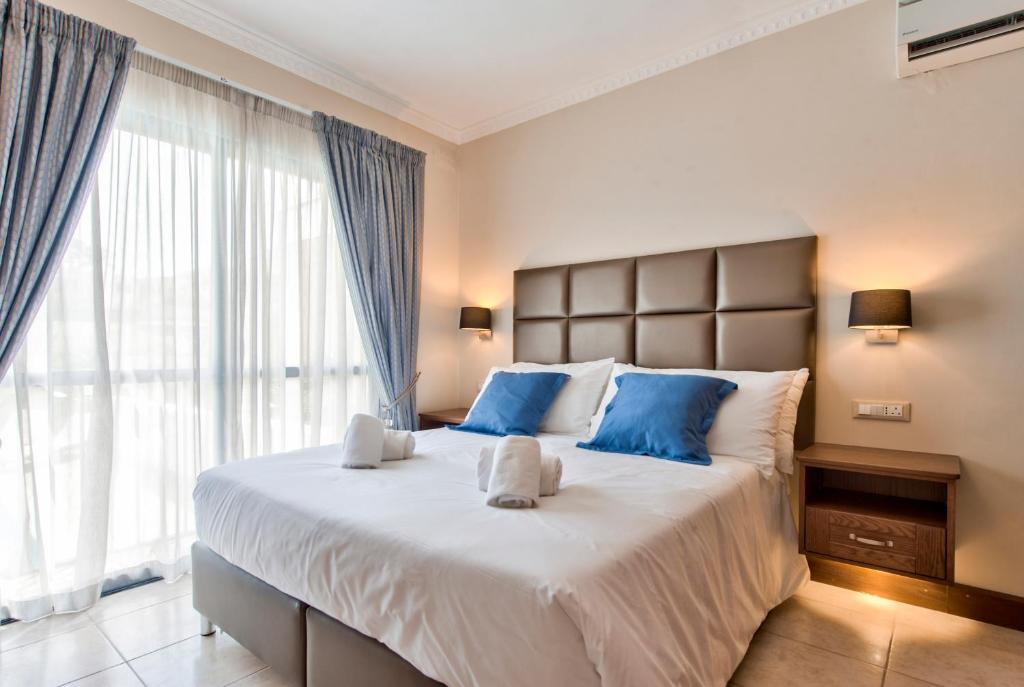 a bedroom with a large bed with blue pillows at Baldacchino Holiday Villas in Mellieħa
